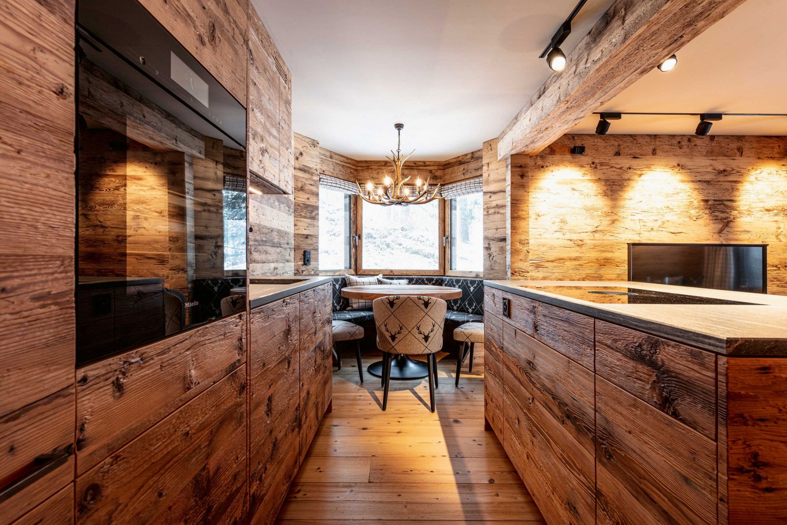 Die Küche aus altem Holz ist eine Eigenkreation von Schoepf Living und fügt sich nahtlos ins Interieur ein. Im passenden Stil vollenden Tisch und Stühle das Ensemble.