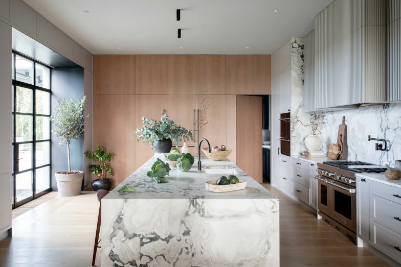 Für die Küche verbinden die InnenarchitektInnen den klassischen Landhausstil mit modernen Elementen. Ein echter Blickfang sind Insel und Rückwand aus Marmor. In Kontrast dazu steht das gekalkte Eichenparkett.