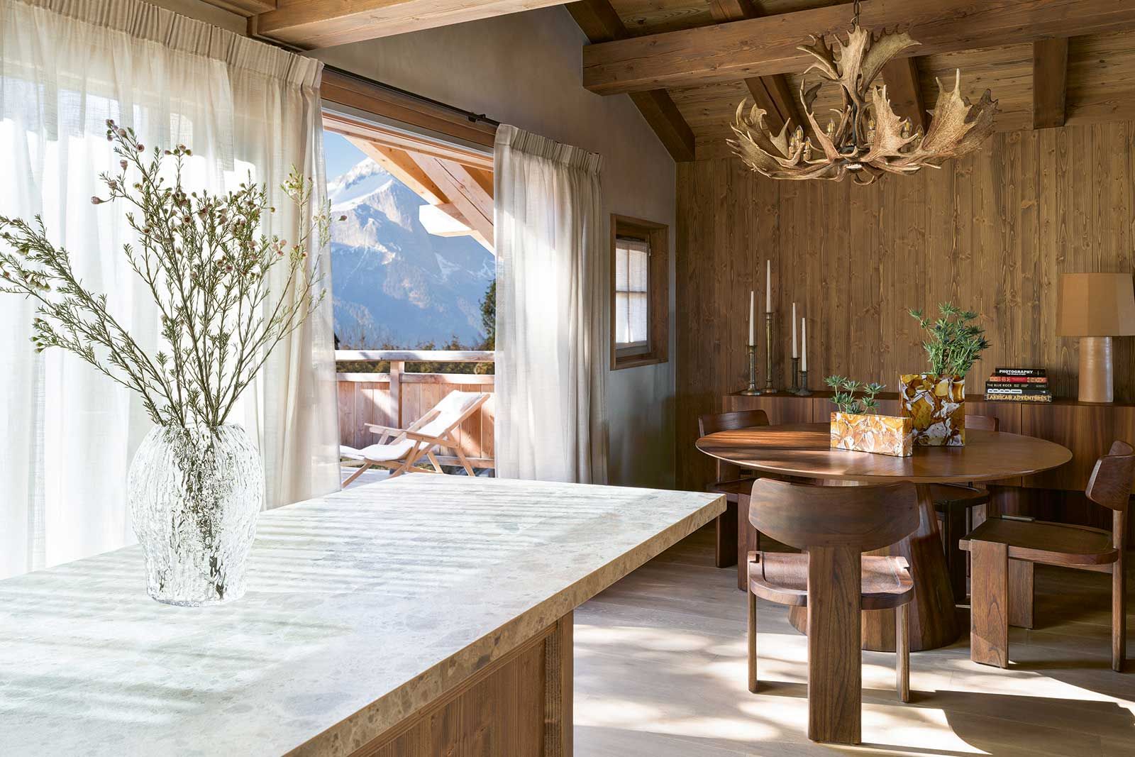 Im Essbereich spannt sich über dem runden Tisch von Versmissen ein Kronleuchter aus Geweihen wie ein natürlicher Blickfang. Das Licht dazu spendet eine schlichte Pendelleuchte von Vibia. Die Vasen von Simona Sbordone für Brokisglass fügen sich als filigranes Detail ein. Das Sideboard «Giunone» von Mogg komplettiert den Raum.