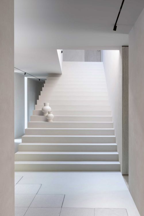 Der unbestrittene Star des Hauses ist die monolithische Treppe im Eingangsbereich. Sie verzichtet auf jegliche dekorativen Elemente und strahlt rein aufgrund ihrer Form Eleganz und Grandezza aus.