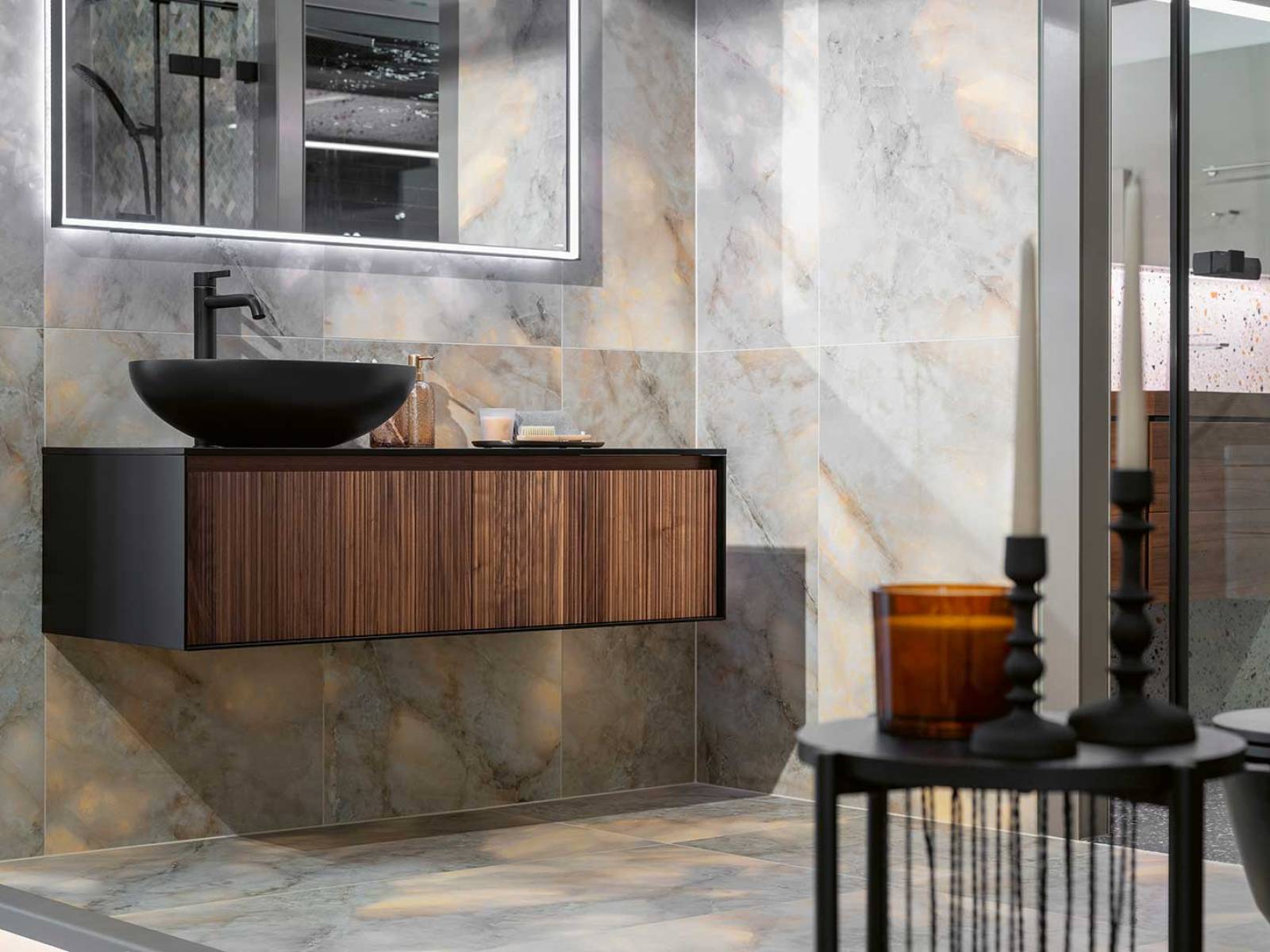 Feinsteinzeugplatten in matter und polierter Marmor-Bernstein-Optik treffen auf einen Unterbau in matt lackierter Holzstruktur und bringen Eleganz ins Bad. Der schwarze Aufsatzwaschtisch «Zante» und der passende Waschtischmischer «Bevo» setzen moderne Akzente. Das Unternehmen besitzt schweizweit fünf Ausstellungen für Bäder, Wand-, Bodenplatten und Parkett. HUG BAUSTOFFE.