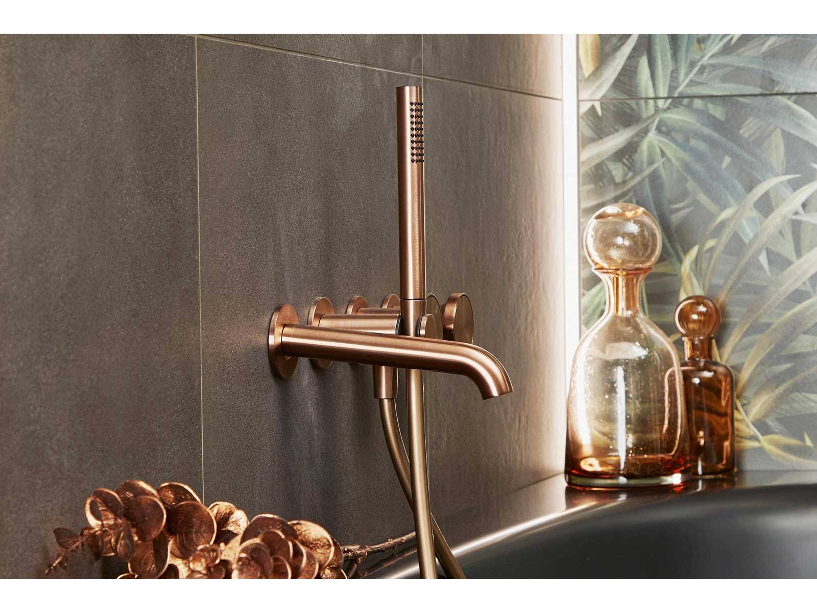 Dieses Badezimmer verströmt eine glamouröse, verspielte Ästhetik mit modernem Ambiente. Armaturen aus gebürstetem Kupfer schaffen ein luxuriöses Flair. Dunkle Töne und natürliche Holzelemente ergänzen die exotisch inspirierte Wandgestaltung zu einem Wohlfühlraum aus hochwertigem Materialmix und liebevollen Details. SABAG.