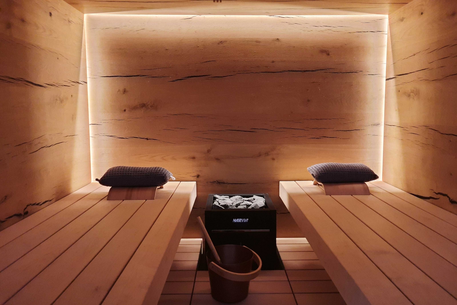 Eiche rissig ist bei dieser Sauna das gewählte Holz. Es wurde fugenlos im Innenbereich verarbeitet. Durch die indirekte Beleuchtung, welche die Rückwand umläuft, bekommt die Sauna optisch mehr Tiefe. Das Licht kann je nach Bedarf gedimmt werden. SAUNAWORLD.CH