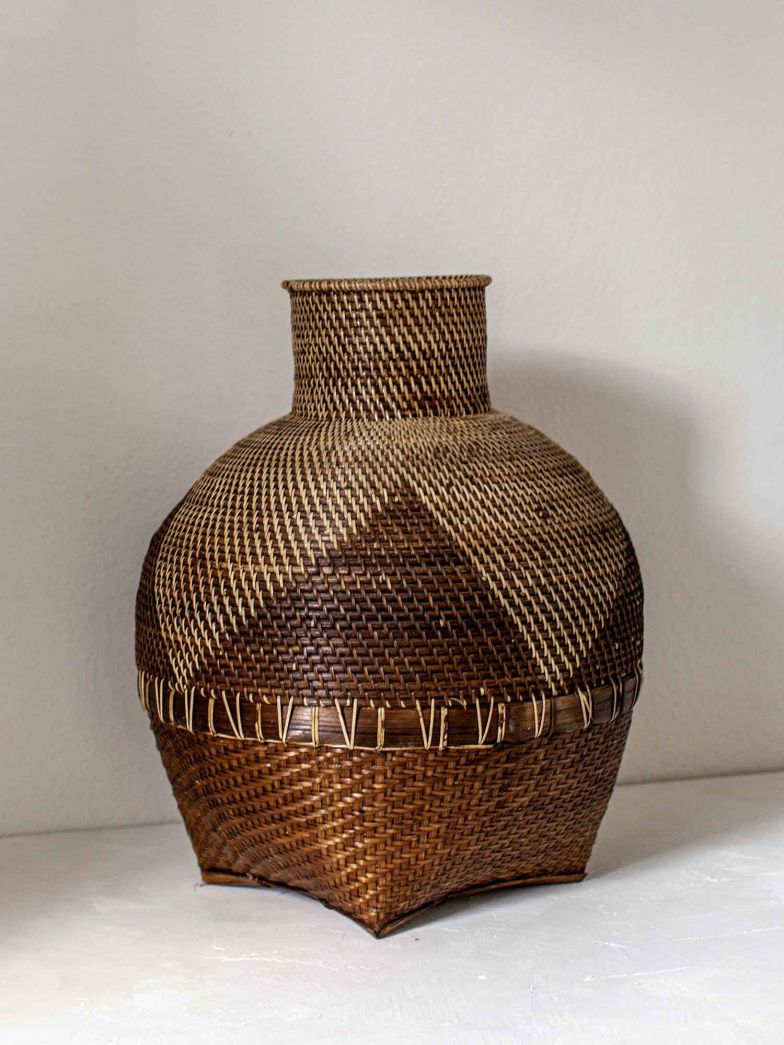 Dieser handgewebte, vasenförmige Korb wird aus Rattan gefertigt und kann mit getrockneten Zweigen oder Pampasgras dekoriert werden.