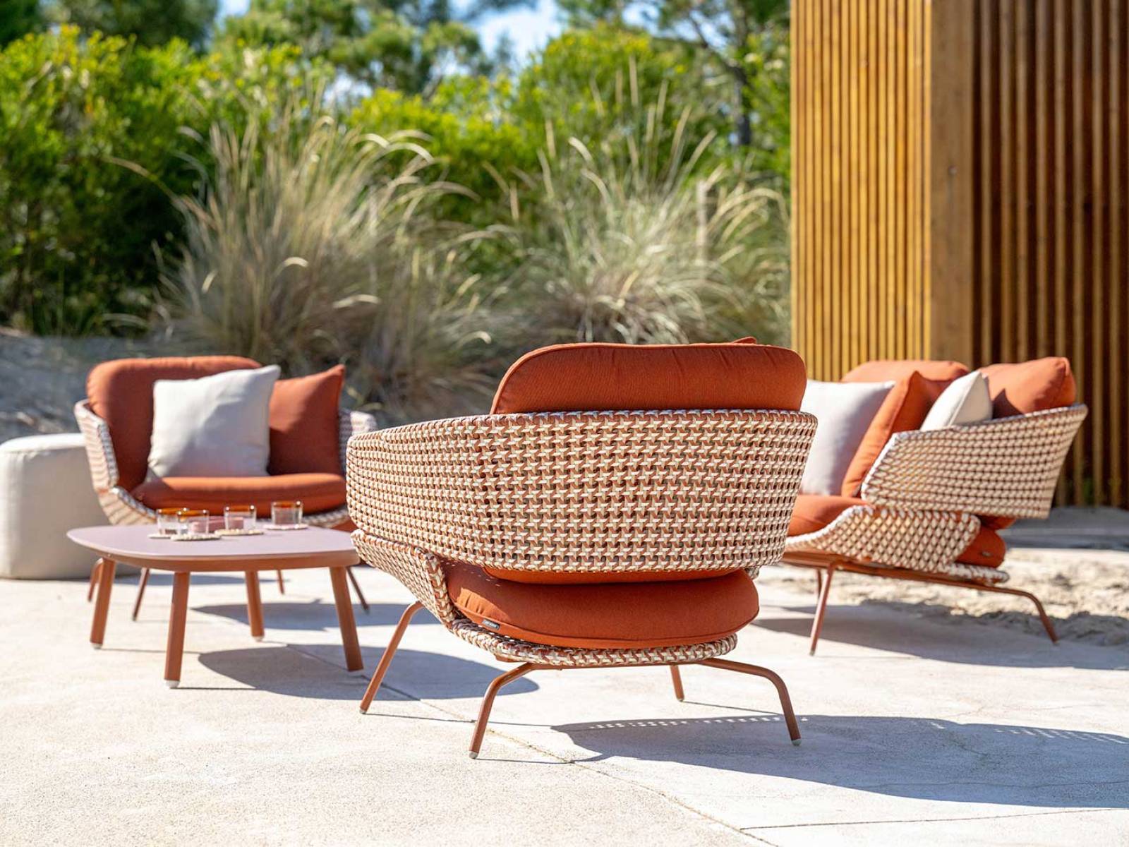 «Santiago» bringt sommerliche Leichtigkeit in den Aussenbereich: Handgeflochtenes Polyrattan in Forest Grün, Stone Beige und Urban Terracotta verdichtet sich zu einem kompakten Muster, das das Edelstahlgestell in Naturtönen umspielt und die ausdrucksstarke Präsenz der Gartenlounge unterstreicht. Foto: © studiovision.be, Raf Ketelslagers & Ruud Lathouwers. HUNN GARTENMÖBEL.